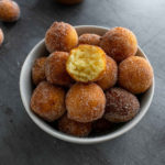 a bowl filled with ricotta doughnuts and one which is half eaten