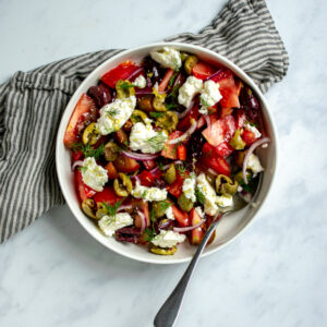 A plate of tomato salad with olives and cheese